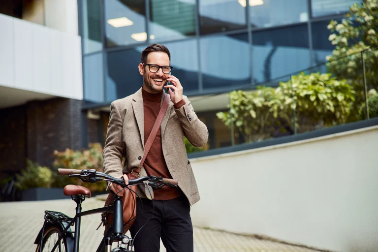 Un homme au téléphone marchant à côté de son vélo dans la ville.