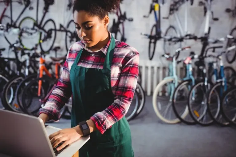 Une employée d'un magasin de vélo gère ses réservations sur un ordinateur.