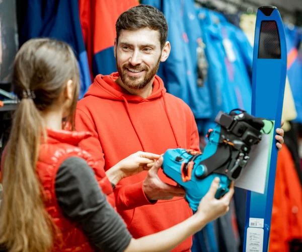 Un homme et une femme choississent des équipements de sports, regardent les bottes et les skis