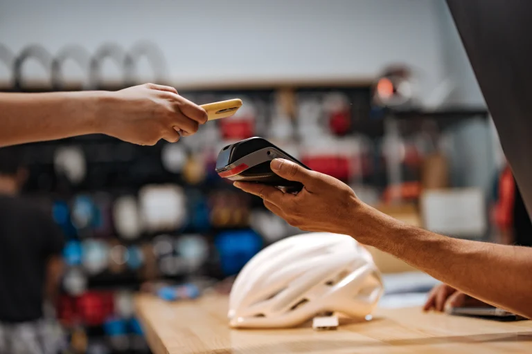 Une personne paie son casque de vélo avec une carte bancaire. Le vendeur tend un tpe en direction de l'acheteur.